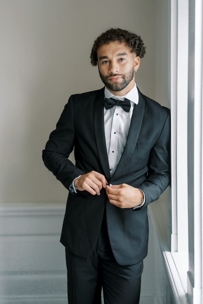 The French House groom in black tuxedo buttoning blazer