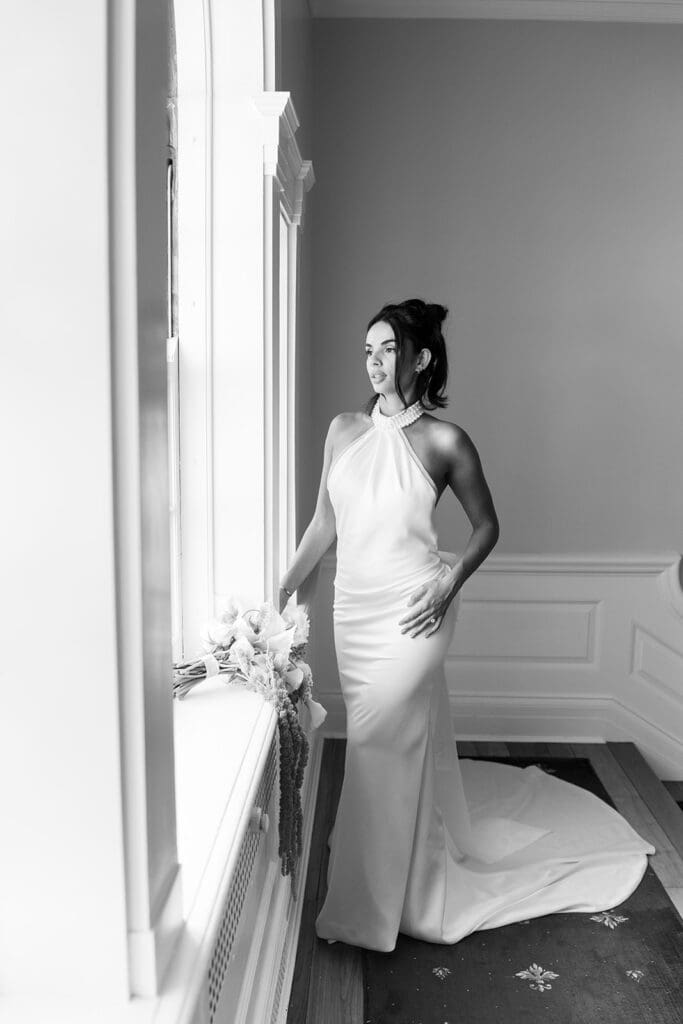 Bride in black and white looking out window inside The French House