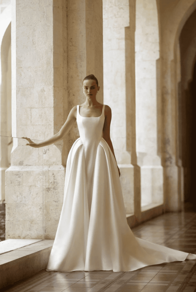 wedding gown with clean square neckline and dramatic architectural side pleats