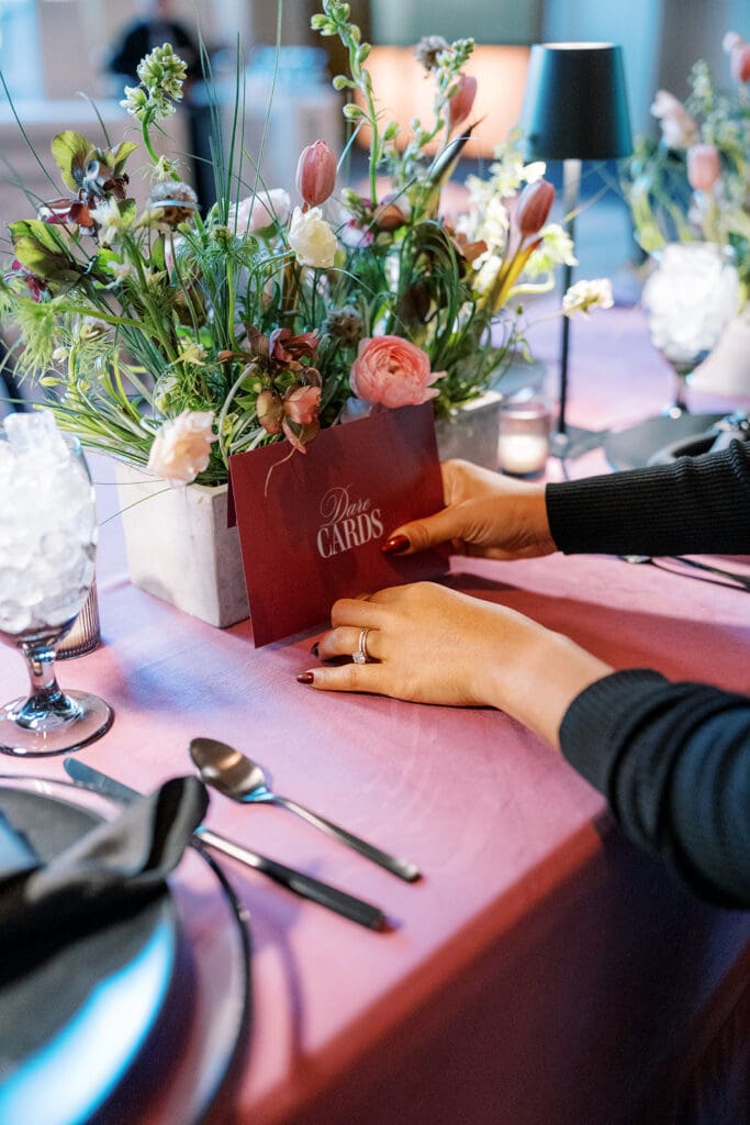 Wedding planner placing dare card stationery on reception table